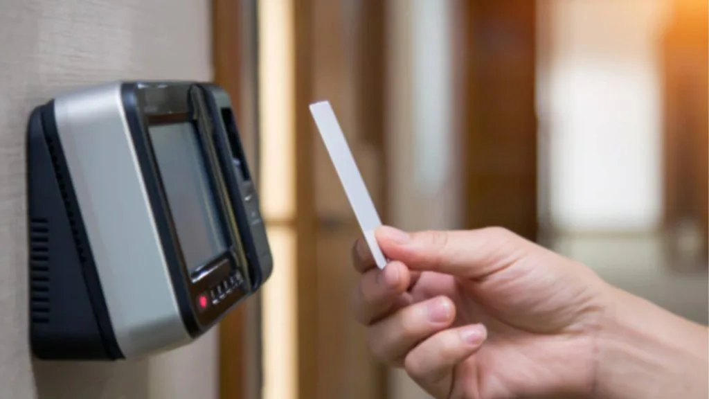 Hand holding an access card in front of a card reader device integrated with Gprop Systems access card system.